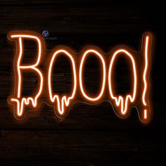 the word boo spelled with neon lights on a wooden surface in front of a dark background