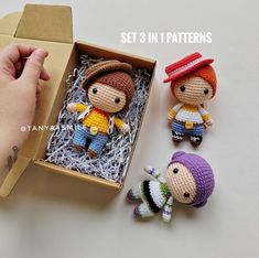 two small crocheted dolls sitting next to each other in a box on a table