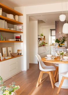 the dining room table is set with white chairs, and there are bookshelves in the background