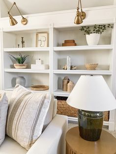 a living room filled with white furniture and lots of bookshelves on top of them