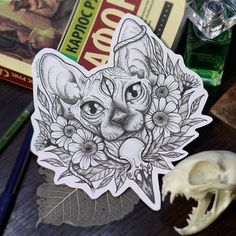 a cat sticker sitting on top of a table next to a skull and some books