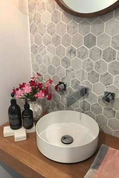 a white sink sitting on top of a wooden counter next to a vase with flowers