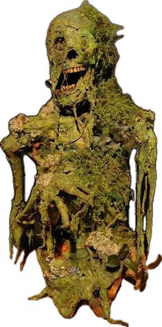 a statue made out of moss with an evil look on it's face and hands