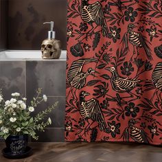 a red shower curtain with black birds and flowers on it next to a white skull