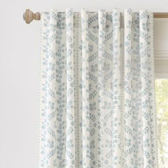 the curtains are hanging on the window sill in front of an open window with white and blue floral print