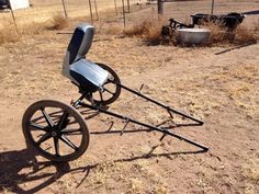 an old fashioned horse drawn buggy sitting in the middle of a dirt field next to a fence