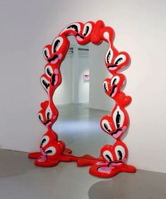 a mirror that is sitting on the ground in front of a wall with red and white decorations