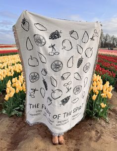 a woman is standing in front of a field with tulips and other flowers