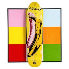 a skateboard with a banana painted on it next to multi - colored squares and a black frame