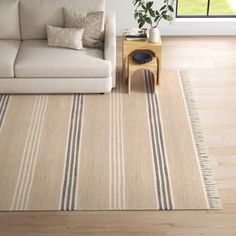 a living room with a white couch and striped rug on the floor next to a window