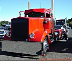 an orange semi truck parked in a parking lot