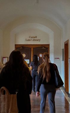 two women are walking down the hallway in front of an entrance to a law library