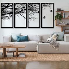 three black and white paintings on the wall above a couch in a living room with a coffee table