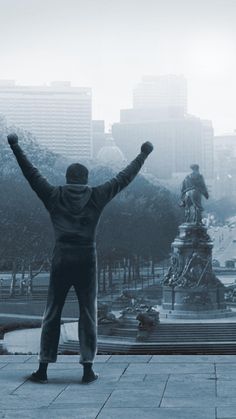 a man standing in front of a statue with his arms up