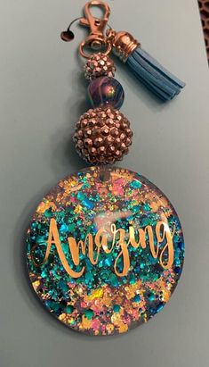 an acrylic keychain with the word amazing on it and a tassel