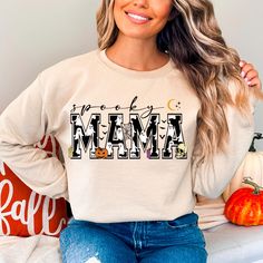 a woman sitting on a couch wearing a sweatshirt that says mama