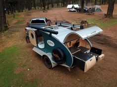 a camper trailer parked in the woods with its door open