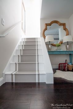 the stairs in this house have been painted white and are next to a mirror with a woman's face on it