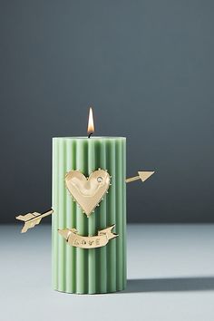 a green candle with an arrow and heart on the top, surrounded by gold arrows