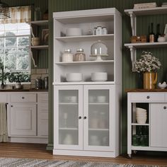 a kitchen with green walls and white cupboards in the center, filled with dishes