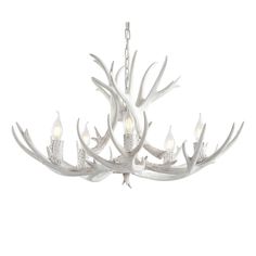 a white chandelier with antlers hanging from it's center and two candles in the middle