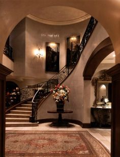 an elegant entry way with flowers in a vase on the table and stairs leading up to it