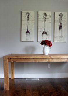 a vase with flowers sitting on top of a wooden table next to two framed pictures