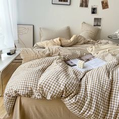 an unmade bed with brown and white checkered comforter on top of it