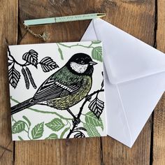 a card with a bird sitting on top of a tree branch next to an envelope