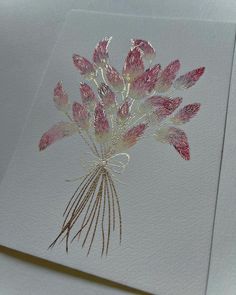 a bouquet of pink flowers sitting on top of a white card with gold foiling