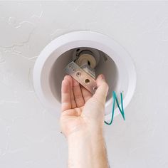 a person adjusting the light bulb on a ceiling fan with a green cord attached to it