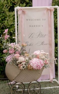 a baby carriage filled with flowers next to a welcome sign