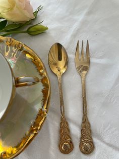 two forks, spoons and a plate on a table with flowers in the background