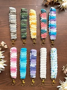 six crocheted key fobs are lined up on a table with flowers