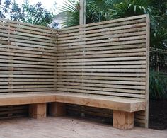 a wooden bench sitting on top of a cement floor next to a lush green forest