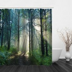 a bathroom with a shower curtain that has sunlight coming through the trees in the woods