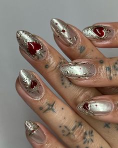 a woman's hand with some silver and red nail polish on her nails,