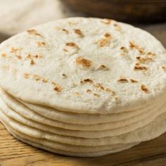 a stack of tortillas sitting on top of a wooden table