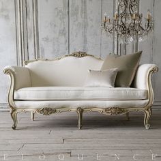 a white couch sitting on top of a wooden floor next to a chandelier