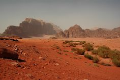 the desert is covered in red sand and rocky mountains are seen in the back ground