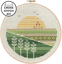 the cross stitch kit has been designed to look like a landscape with trees and grass