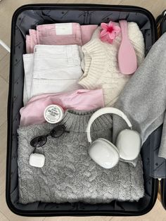 an open suitcase filled with clothing and headphones