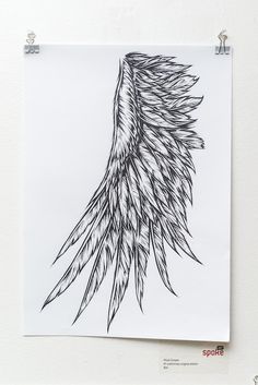 a black and white drawing of a wing on a piece of paper hanging on a wall