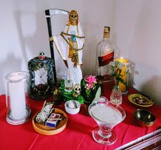 a table topped with lots of items like a statue, candles and other things on top of it