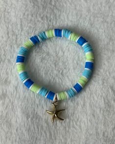 a bracelet with a starfish charm on it sitting on top of a white blanket