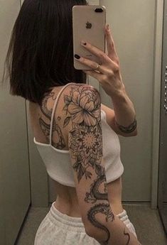 a woman is taking a selfie in the mirror with her phone and arm tattoo