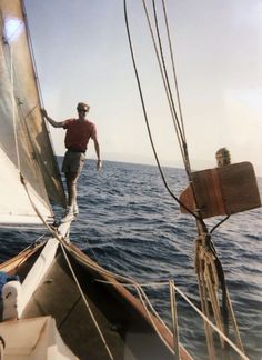 a man standing on the side of a sail boat