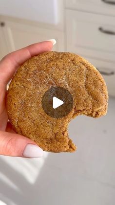 a person holding a cookie in their hand with a video playing button on the top