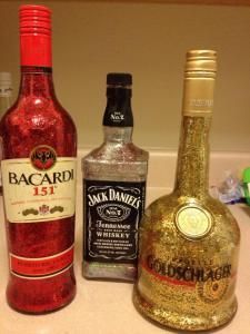 three bottles of alcohol sitting on top of a counter next to toothbrushes and other items