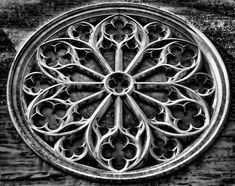 a circular window with an intricate design on the side of a wooden building in black and white